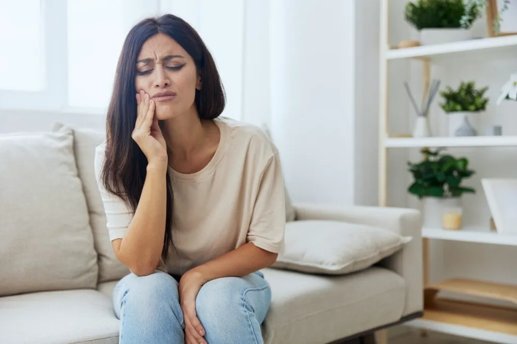 Woman toothache, tooth root inflammation sitting on sofa at home. High quality photo