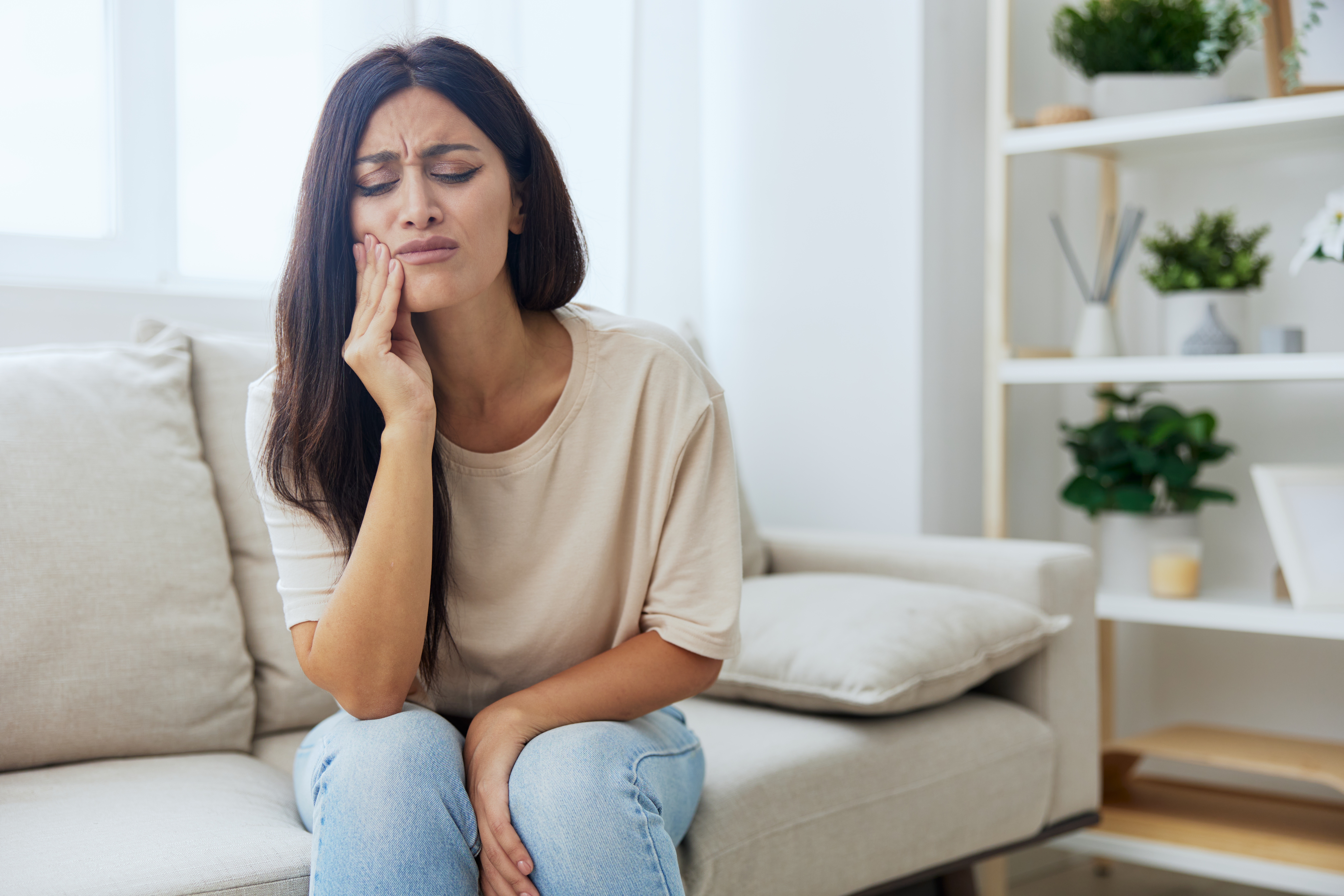 Woman toothache, tooth root inflammation sitting on sofa at home. High quality photo