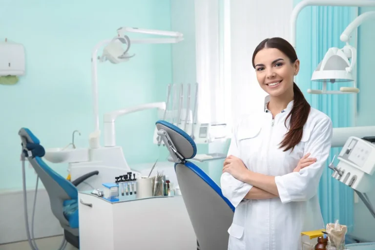 Young female dentist in white coat at workplace. Space for text