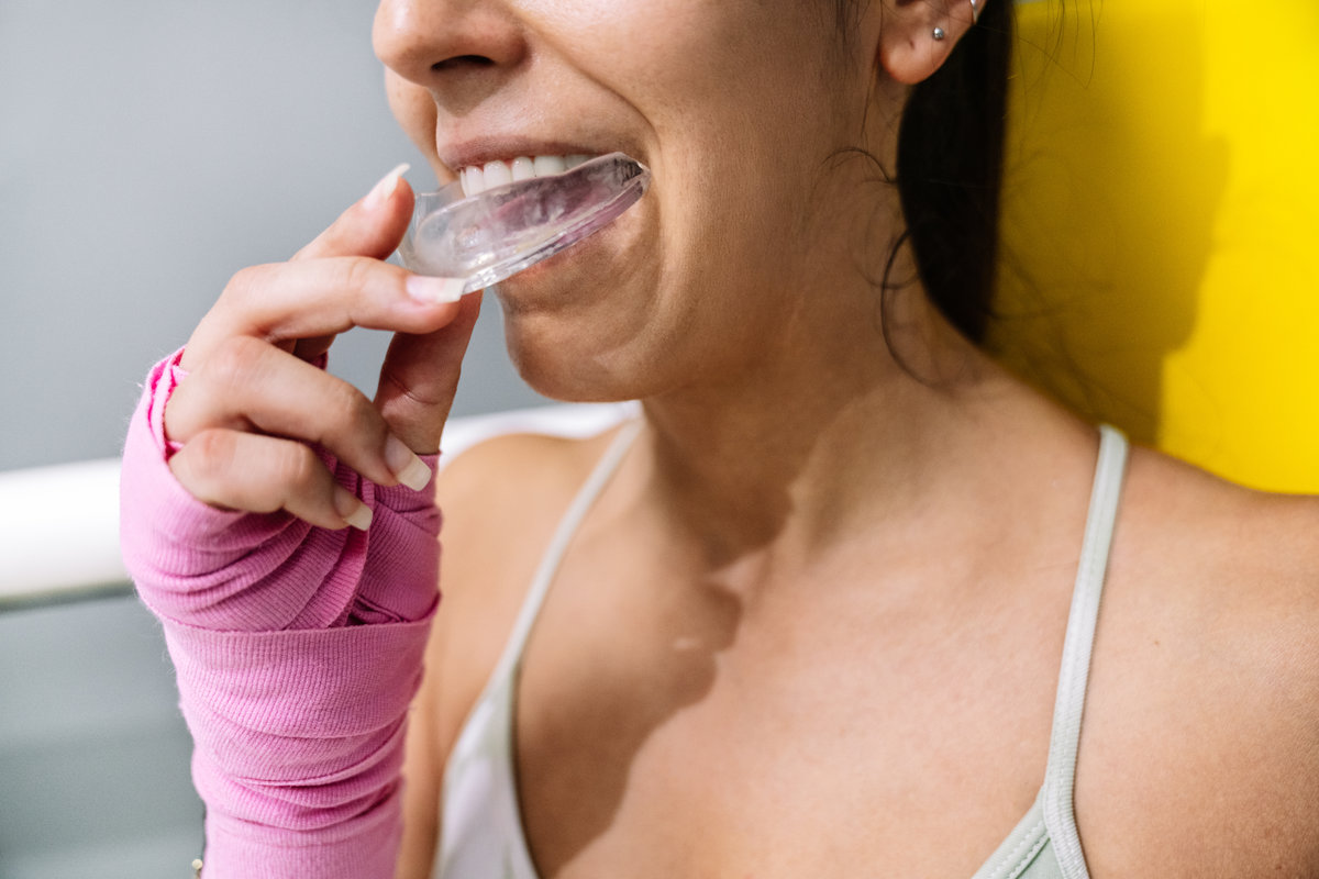 Midsection of a female athlete putting on a mouth guard in boxing training in a ring.