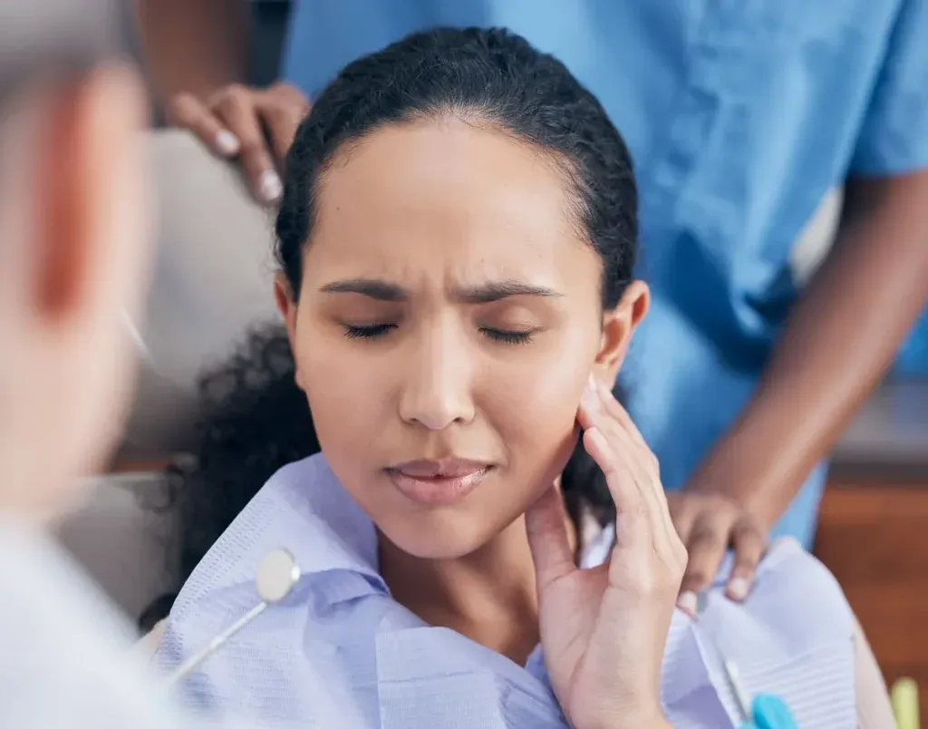 Toothache, woman and pain at dentist for consultation with discussion, problem and tooth injury for medical dental treatment. Patient, orthodontist and appointment for extraction help of gum disease