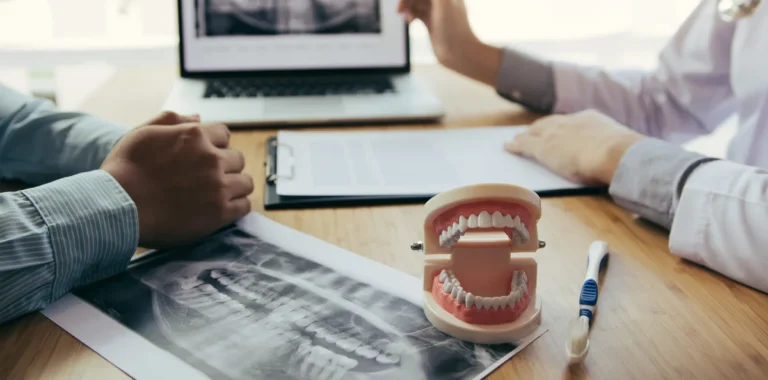 Dentist reviewing a dental x-ray with a patient to discuss implant treatment and longevity